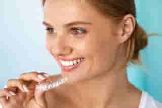 Smiling women holding clear aligners
