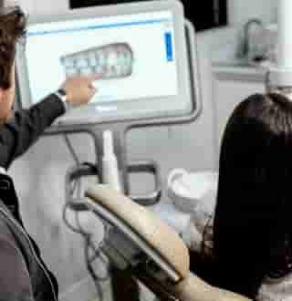 Smiling blonde women in her 20s holds Invisalign clear aligners near her teeth